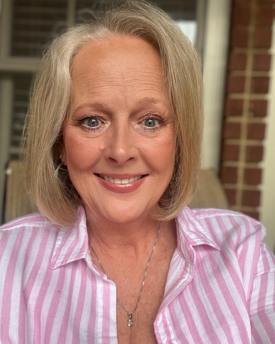 Ann Keller UGC Creator for GEN X and Beauty Brands Ann Keller UGC Creator sitting in a chair with a pink and white striped shirt on.